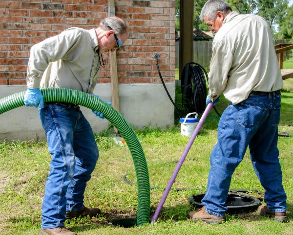 Two men working with hoses on a grassy lawn.
