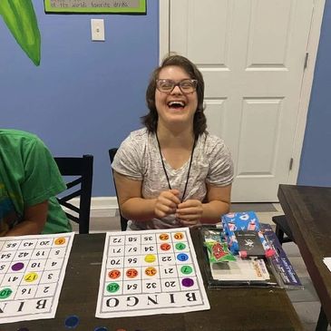 A girl happily playing bingo at a table.