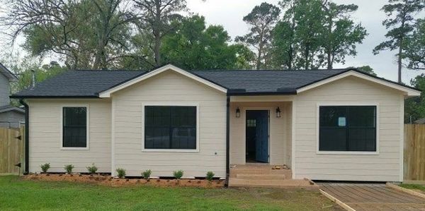 Newly built single-story house with black roof and multiple windows.