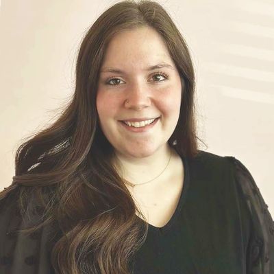Smiling young woman with long brown hair wearing a black top.