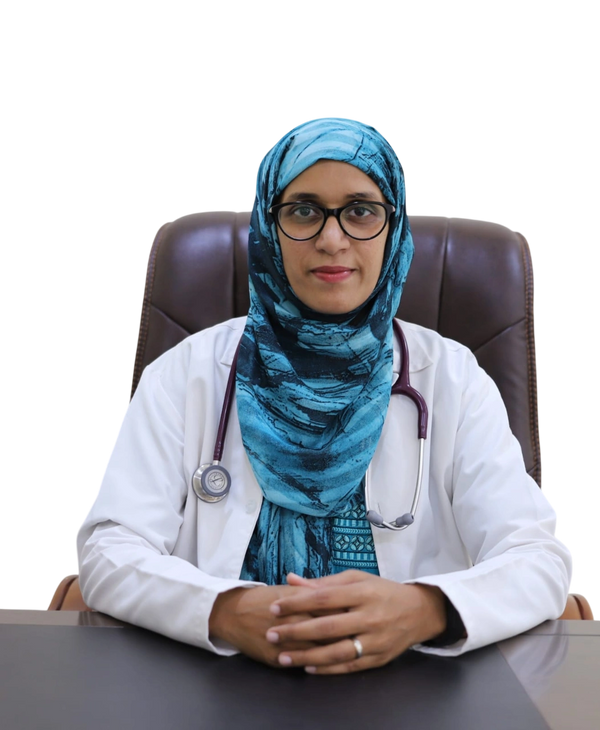 Female doctor with a blue hijab and stethoscope sitting at a desk.
