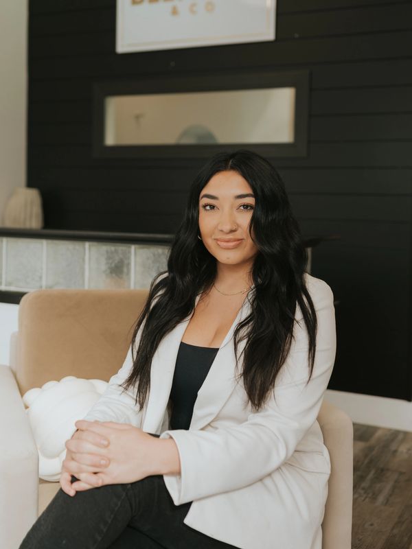 Confident woman sitting in a stylish office with a BLENDED & CO sign behind.