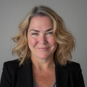 Smiling middle-aged woman with blonde hair in a black blazer.