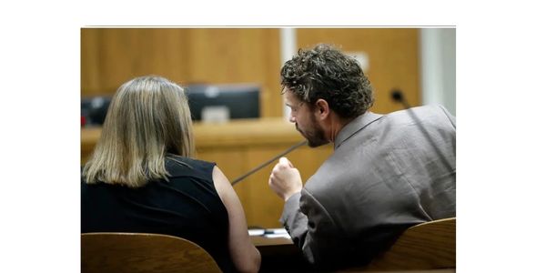 Two people engaged in a serious discussion in a courtroom setting.