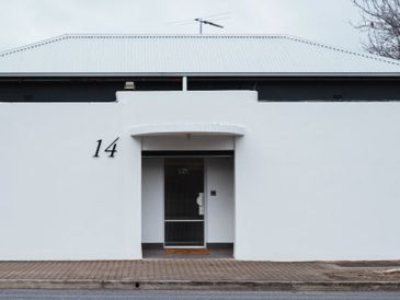 Minimalist white house facade with the number 14 and a simple door.