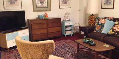 Mid-century modern cabinets, wing chair, and knick-knacks in Saskatoon Cottage.