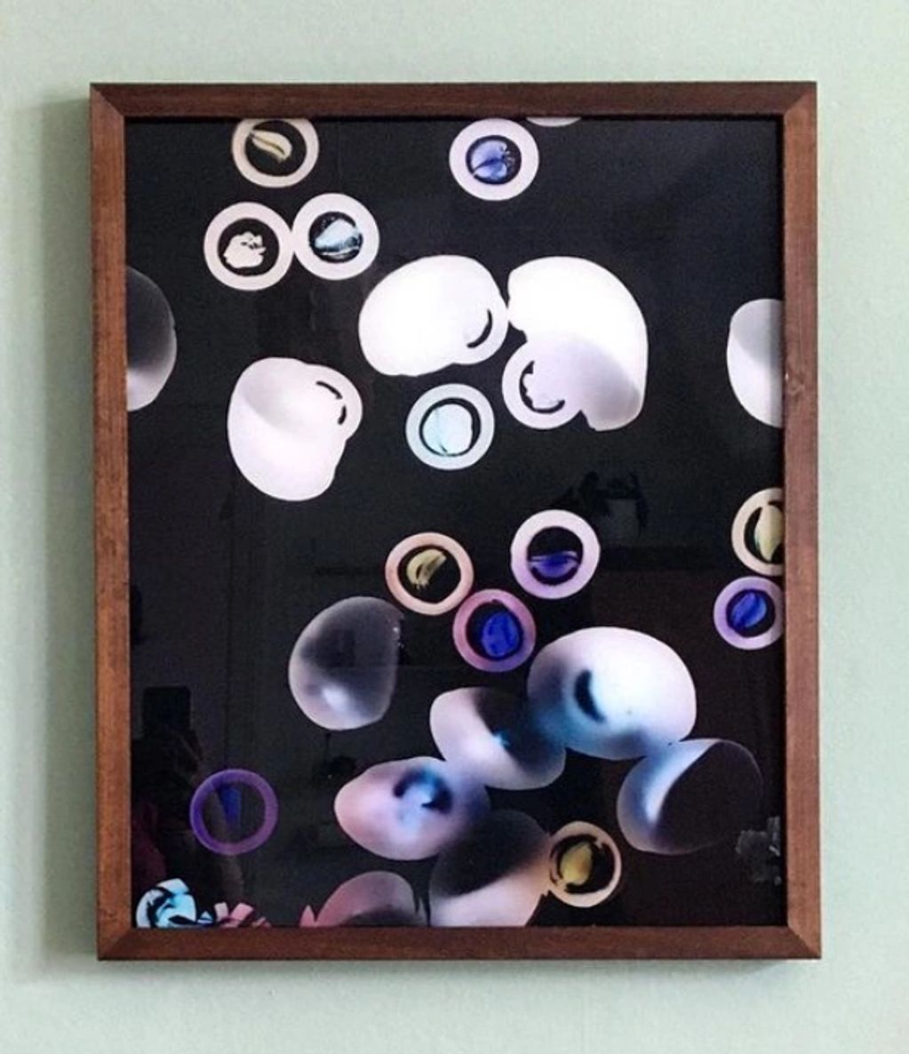 Abstract art with floating circular shapes in a wooden frame.