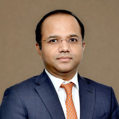Professional man in a blue suit and orange tie with glasses.