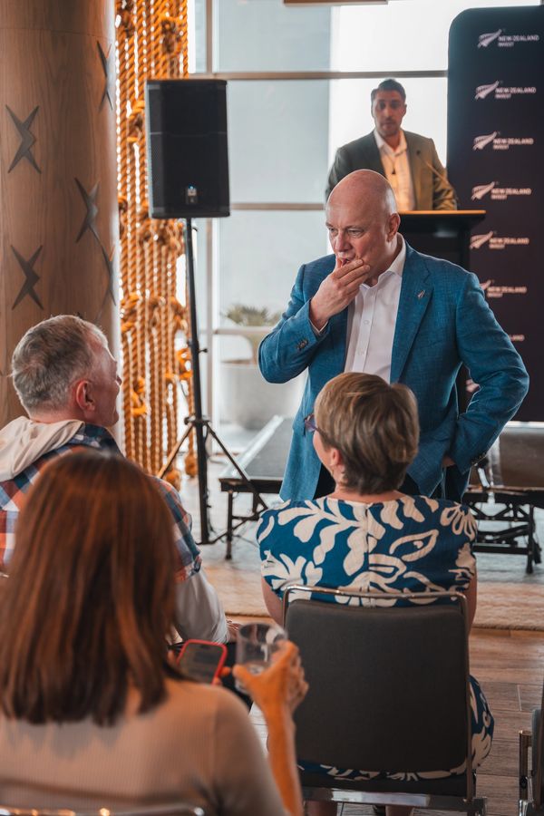 A man in a blue blazer thoughtfully interacts with an audience during a presentation.