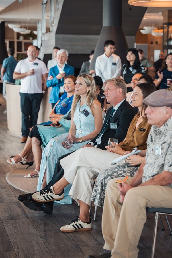 A diverse group attentively listens at a professional indoor event.