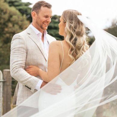 A joyful bride and groom share a loving moment outdoors on their wedding day.
