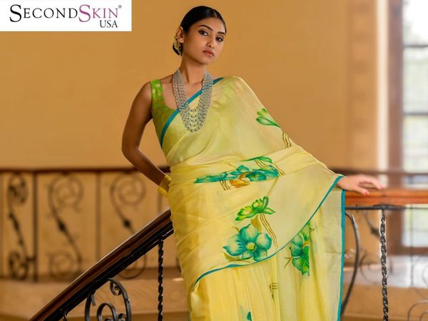 Elegant woman wearing a yellow floral saree with silver jewelry indoors.