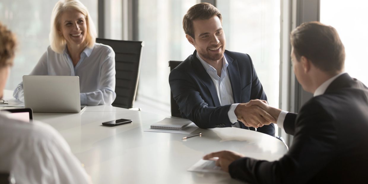 Happy business partners shaking hands with respect.