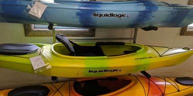 Three kayaks on a rack inside of a rental shop.