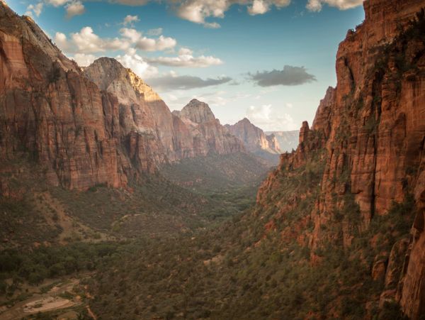 Large green valley with huge red rock formations and mountains coming up on either side