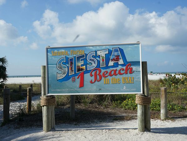 Siesta Key beach sign in front of white sand beach