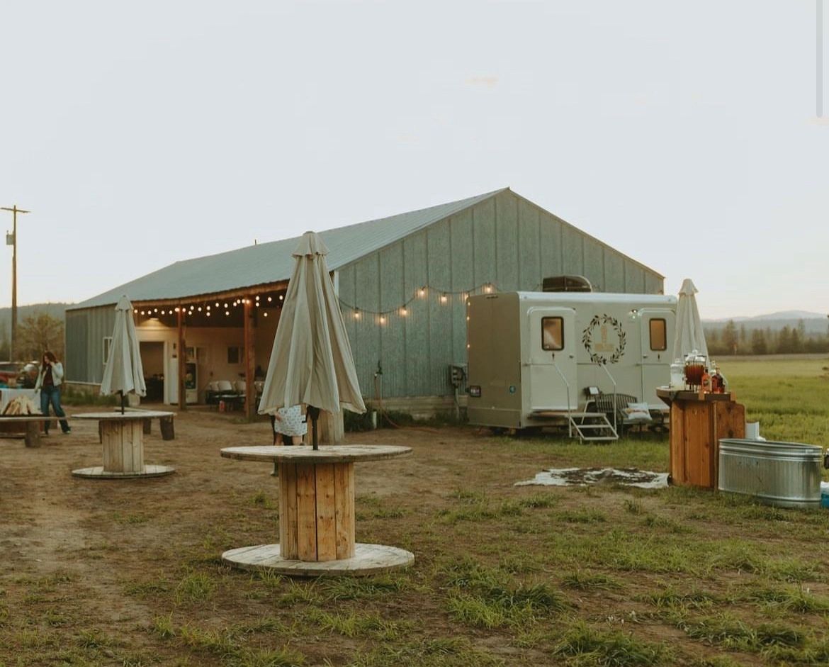 sepia tone view of a restroom trailer set up in front of a barn in a rustic setting