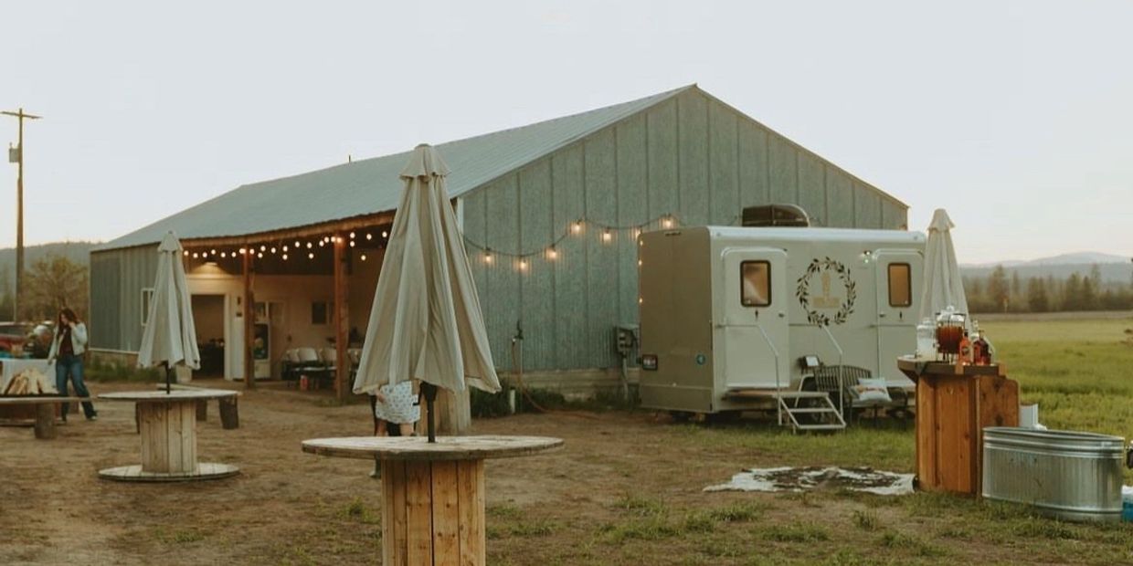 sepia tone view of a restroom trailer set up in front of a barn in a rustic setting