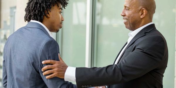 Two men engaged in a serious conversation, one comforting the other.