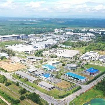 A large industrial complex surrounded by greenery and roads.