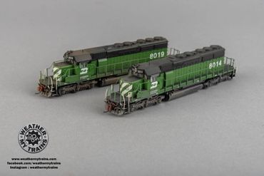 Two detailed green model trains on a gray surface.