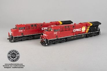 Two detailed model trains painted in red, black, and yellow with CPKC logos.