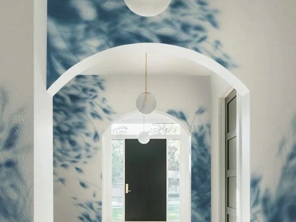 Sunlight casts intricate blue leafy shadows in an arched hallway.