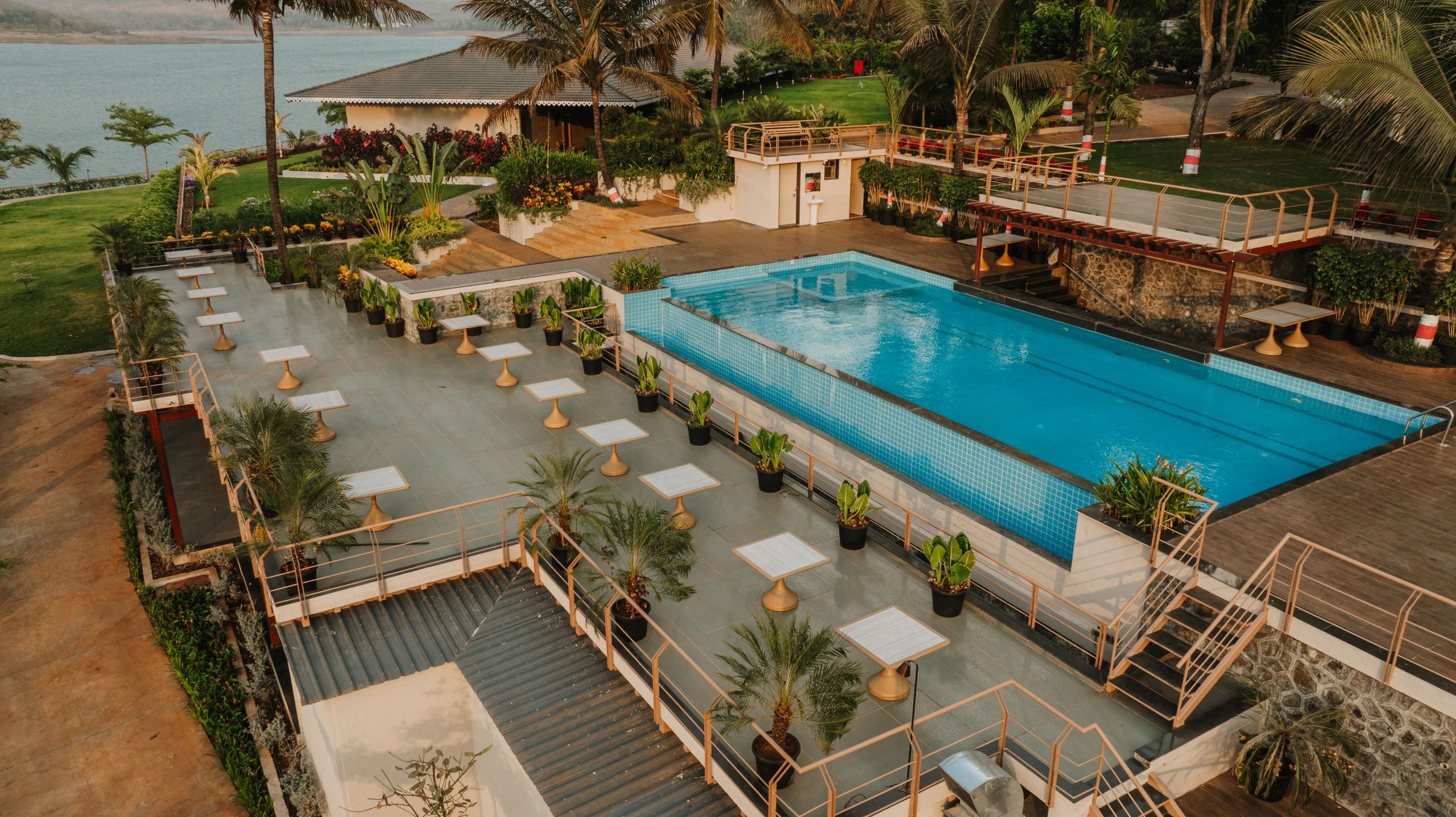A serene outdoor pool surrounded by palm trees and seating areas with lake view.
