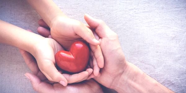 Hands holding a red heart symbolizing attachment theory coaching and emotional safety.