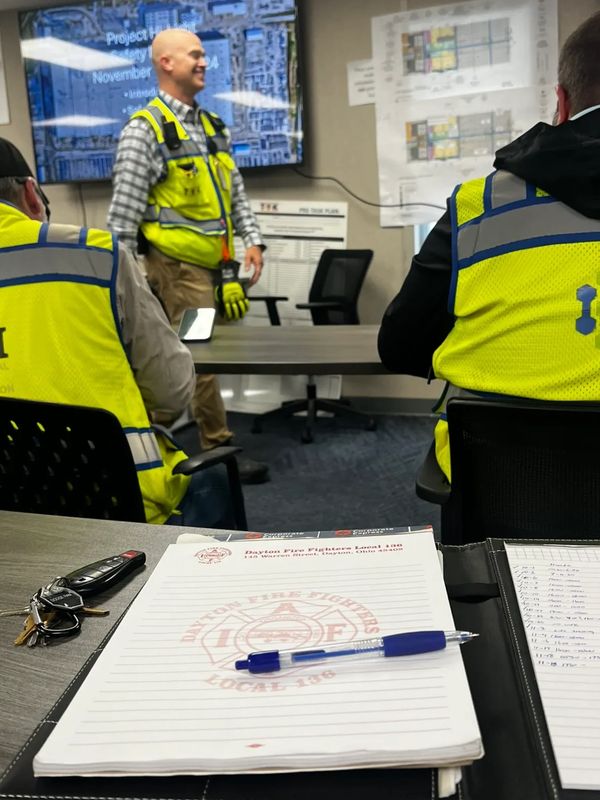 Workers in safety vests attend a project meeting in a conference room.