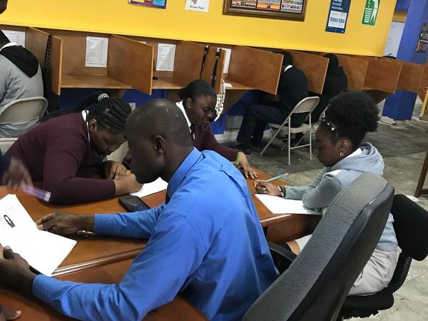 Students studying together with teacher in a classroom with individual study cubicles.