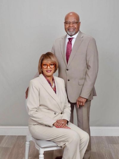 A professionally dressed couple posing against a plain background.