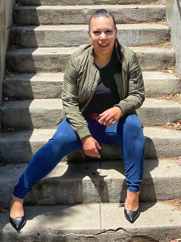 Owner Nichol Soto sitting on concrete stairs for a still photo.
