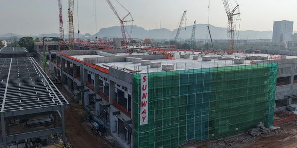 Large building under construction with cranes and scaffolding.