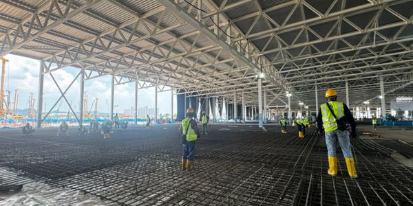 Workers in safety gear at a large construction site.