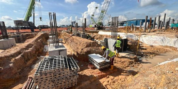Construction workers handling concrete molds on a sunny day.