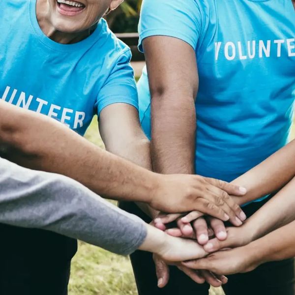 Group of volunteers stacking hands in unity.
