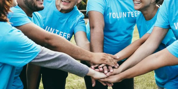 Group of volunteers stacking hands in unity.
