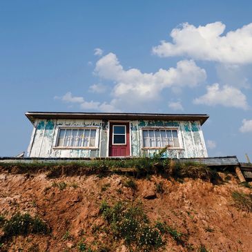 Old house on a cliff under blue sky.