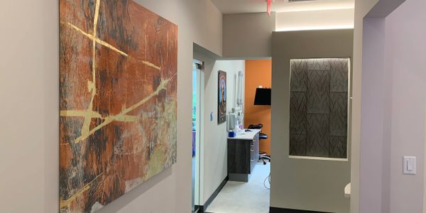 Modern hallway with abstract art and office space at the end.