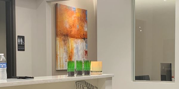 Modern reception desk with abstract art and green plant decor.