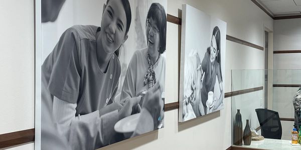 Black and white photos of caregivers interacting with elderly on a wall.