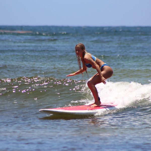 A woman surfing on a small wave in the ocean.