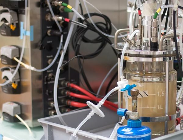 Bioreactor setup with tubes and control panel in a laboratory.