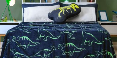 Cama con cobija y almohada de dinosaurios.