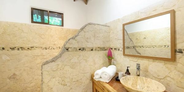 Baño con paredes de piedra y lavabo de piedra.