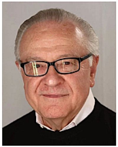 Portrait of an elderly man with glasses and a gentle smile.