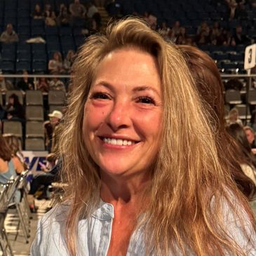 Smiling woman with long blonde hair in a crowded venue.