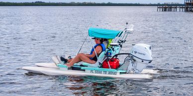 Person relaxing on a small motorized boat with a canopy on calm water.