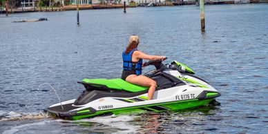 A person riding a green and white Yamaha jet ski on the water.